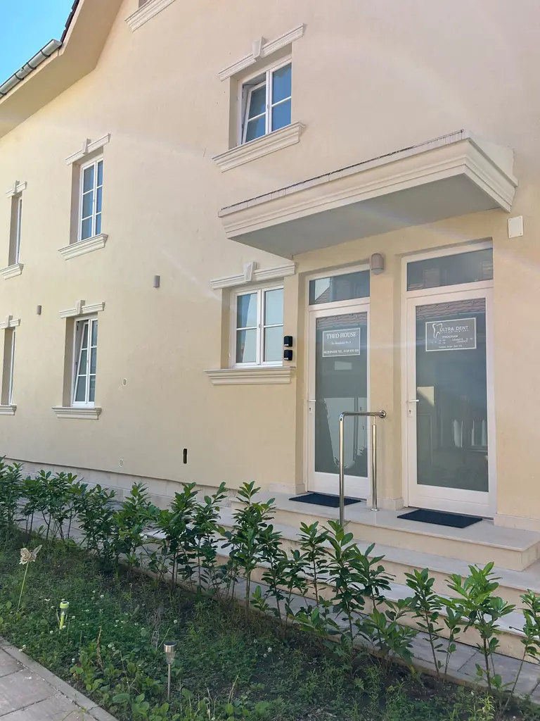 Die Eingangstüren der Ultra-Dent-Klinik, mit Schild und Öffnungszeiten